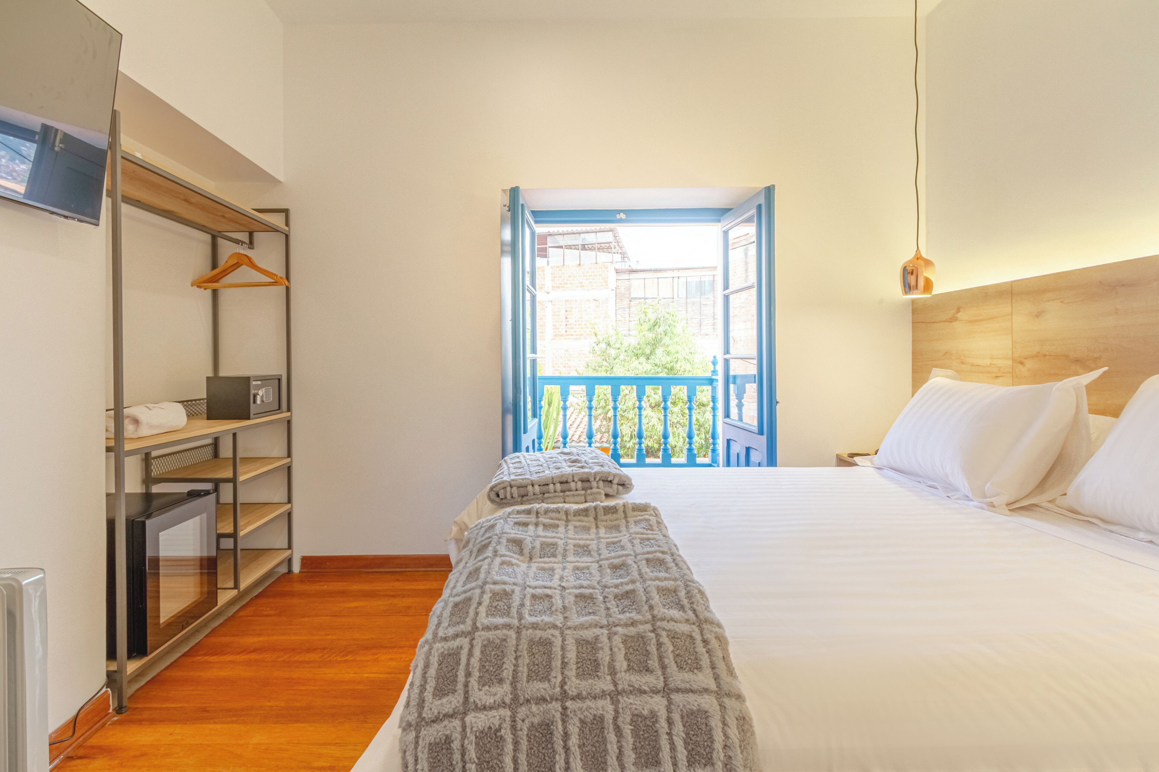 A hotel room with a bed, a wooden headboard, a wardrobe, and a view of the outside.