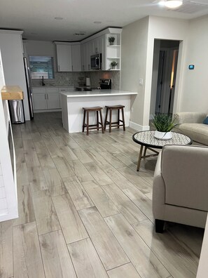 A modern kitchen with white cabinets, a central island, and two stools. - Pet friendly pool oasis in Orlando (Orlando)