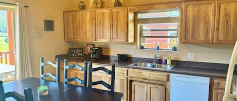 A kitchen with wooden cabinets, a coffee bar sign, a dishwasher, and a dining table with chairs.