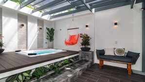 A spa area with a hot tub, seating, and potted plants. - Calla House Arenal 3BR (La Fortuna)