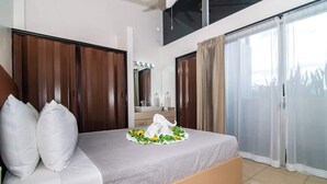 A bedroom with a bed, a large mirror, and a sliding glass door. - Calla House Arenal 3BR (La Fortuna)