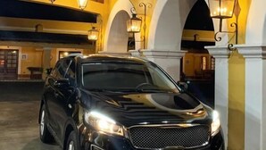 Un coche negro estacionado en un área de estacionamiento techada con techos abovedados y lámparas de pared.