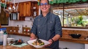 Un cocinero en una cocina sosteniendo un plato de comida.