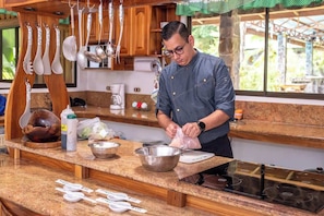 A kitchen with wooden cabinets, a granite countertop, and various utensils hanging above.