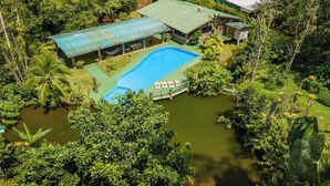 Vista aérea de un resort con piscina, zona cubierta y exuberante vegetación.