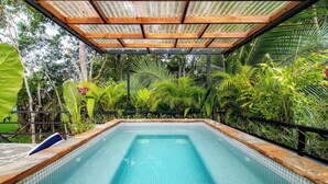 A rectangular pool with tiled edges, surrounded by lush tropical vegetation and a wooden pergola overhead. - Volcano-Lux Arenal 3BR House (Tanque)
