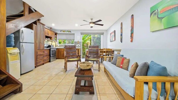 A spacious living area with a sofa, wooden chairs, a dining table, and a kitchen in the background. - Casa Marea Tamarindo (Tamarindo)