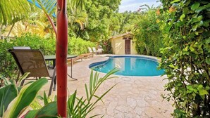 A pool area with a small building, lounge chairs, and lush greenery. - Casa Marea Tamarindo (Tamarindo)