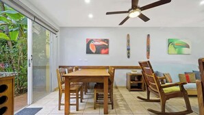 A dining area with a wooden table and chairs, a ceiling fan, and artwork on the walls. - Casa Marea Tamarindo (Tamarindo)