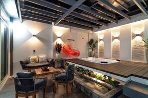 A modern outdoor seating area with a wooden deck, a hot tub, and ambient lighting. - La Fortuna Duo Retreat Villa 6BR (La Fortuna)