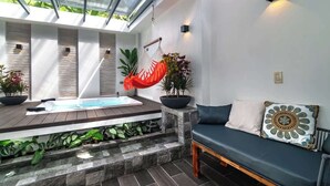 A modern indoor pool area with a seating area, a hanging chair, and a view through a glass ceiling. - La Fortuna Duo Retreat Villa 6BR (La Fortuna)