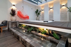 Ein modernes Interieur mit einer Steinsitzbank, einer Hängematte und einem integrierten Pflanzenbeet mit Pflanzen.