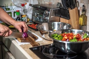 Eine Küchenarbeitsplatte mit einer Person, die eine Zwiebel schneidet, einer Salatschüssel und einem Toaster.