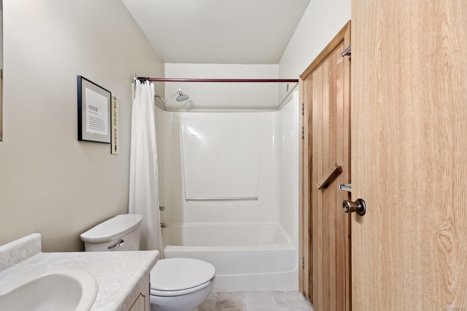 A bathroom with a toilet, sink, shower, and wooden door.