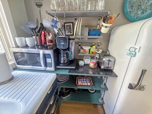 A compact kitchenette with a microwave, coffee maker, toaster, and a small refrigerator. - The Carriage House at Princess Place (Wilmington)