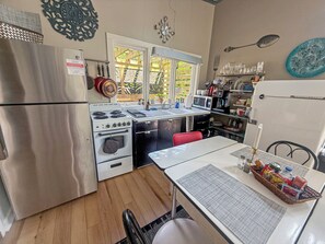 A compact kitchen with a refrigerator, stove, microwave, and sink. - The Carriage House at Princess Place (Wilmington)