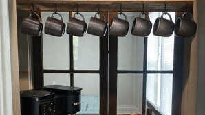 Uma cozinha com cafeteira, chaleira e dosador de grãos de café.