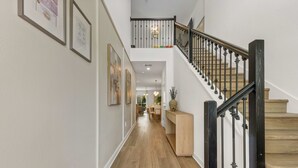 Ein Flur mit Treppe, Holzboden und gerahmten Bildern an den Wänden.