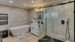 Ein modernes Badezimmer mit einer freistehenden Badewanne, einer Duschkabine und einem Waschtisch mit Spiegel.