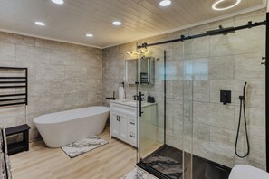Un bany modern amb una banyera independent, dutxa amb envàs de vidre i un lavabo amb mirall.