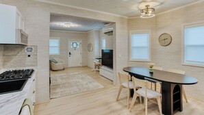 Eine moderne Küche mit Einbauherd, ein Essbereich mit rundem Tisch und Stühlen sowie ein großes Fenster.