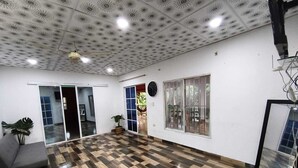 Une pièce spacieuse avec un plafond orné de motifs, une grande fenêtre, une horloge et une plante.