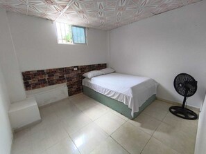 A room with a bed, a window, a fan, and a staircase. - "Finca house near Tayrona with swimming pool and parking". (Calabazo)