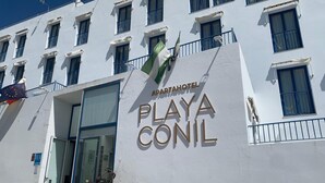 A building with a sign reading 'APARTHOTEL PLAYA CONIL' and a flag. - Apartahotel Playa Conil (Conil de la Frontera)