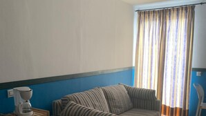 A room with a striped sofa, a coffee maker, and a toaster on a wooden shelf. - Apartahotel Playa Conil (Conil de la Frontera)