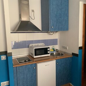 A compact kitchen with a microwave, toaster, and a small refrigerator. - Apartahotel Playa Conil (Conil de la Frontera)