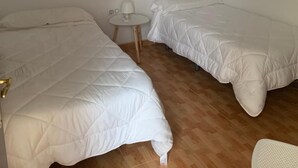 A room with two beds, a small round table with a lamp, and a wall-mounted artwork of a tree. - Apartahotel Playa Conil (Conil de la Frontera)