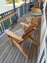 Una terraza de madera con una mesa de vidrio y sillas de mimbre.