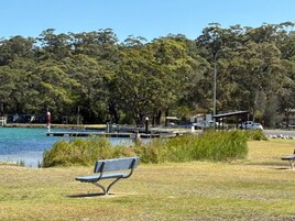 Un parque con un banco, un muelle y una masa de agua.