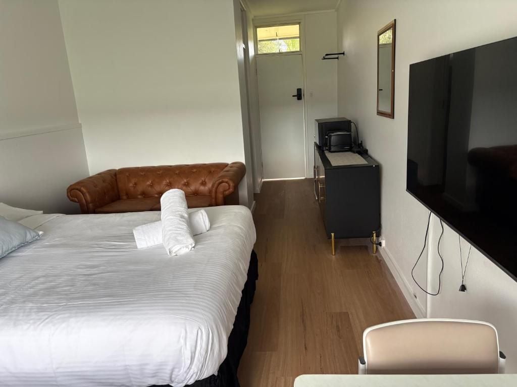 Una camera d'albergo con un letto, un divano, una scrivania con televisore e una sedia.