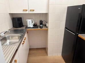 A compact kitchen with a stainless steel sink, a black refrigerator, and a coffee maker on the countertop. - Waterview Motel Sussex Inlet (Sussex Inlet)