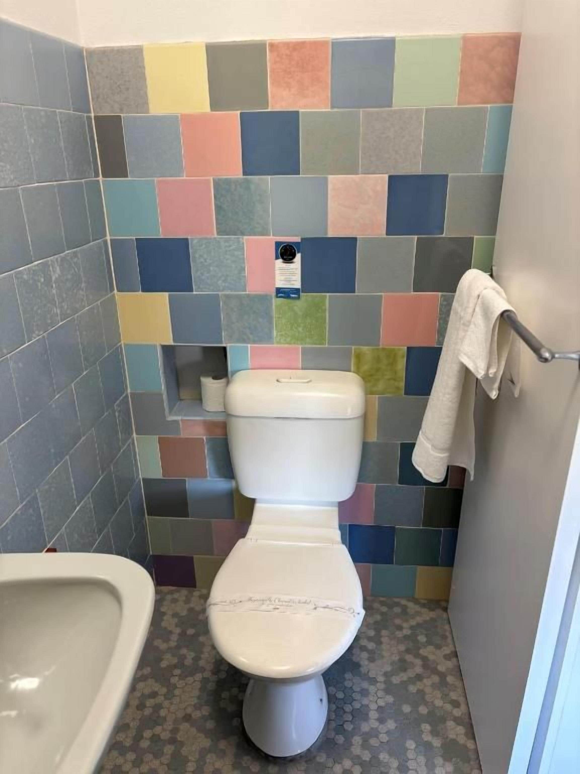 Un baño con inodoro, bidé y pared con azulejos.