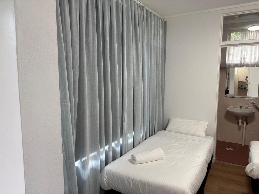 Et hotelværelse med en seng, et badeværelse med vask og et spejl.