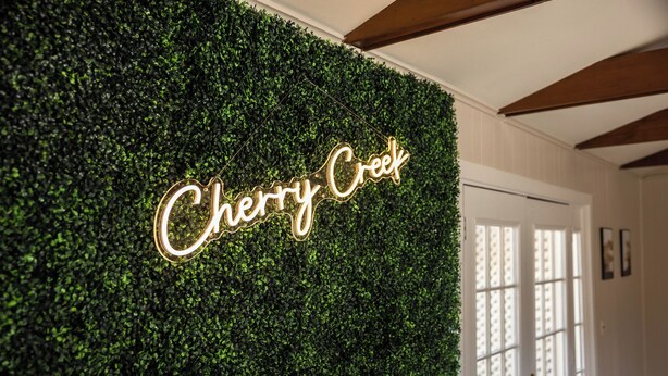 Una pared con un letrero de neón que dice 'Cherry Creek'.