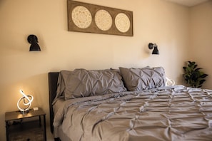 Ein Schlafzimmer mit Bett, Nachttischlampen, einer Wanddekoration und einem Nachttisch.