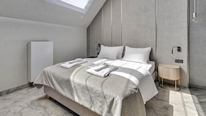 A modern bedroom with a skylight, a bed with neatly folded towels, a bedside table, and a radiator. - Hotel Grano Gdansk SPA & Wellness (Gdańsk)