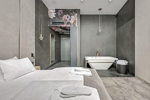 Une chambre d’hôtel moderne dotée d’un grand lit, d’une salle de bain avec baignoire et d’une douche.