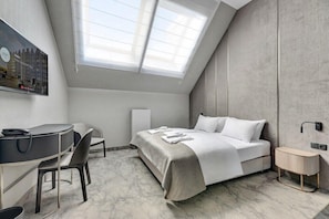 Une chambre à coucher moderne avec une lucarne, un lit, un bureau et une chaise.