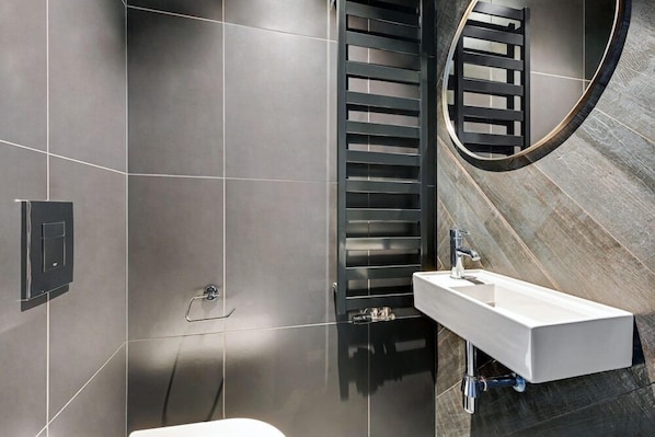 Une salle de bain moderne avec un lavabo rectangulaire, un porte-serviettes et un espace douche.