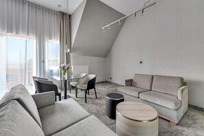 Una sala de estar moderna con un sofá gris, una mesa redonda y un comedor con sillas y una mesa de vidrio.