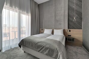 Een moderne hotelkamer met een groot bed, een houten hoofdbord, een nachtkastje en uitzicht.