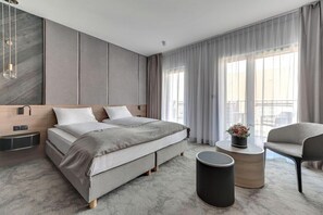 Una habitación de hotel moderna con una cama grande, una mesita auxiliar, una silla y vistas al exterior.