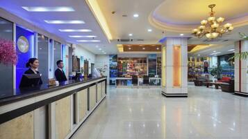 A hotel lobby with a reception desk, a seating area, and a large pillar.