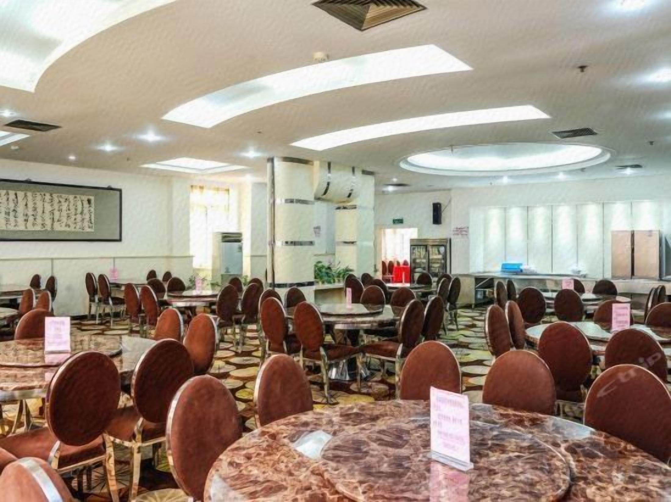 A conference room with multiple round tables and chairs, equipped with name cards and a projector screen.