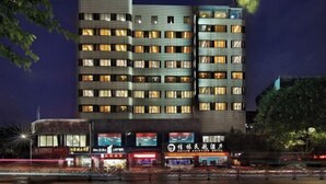 A multi-story hotel with illuminated windows and a ground-level commercial area with various shops. - Minhang Hotel (Guilin Railway Station & Elephant Trunk Hill Park Branch) (Guilin)