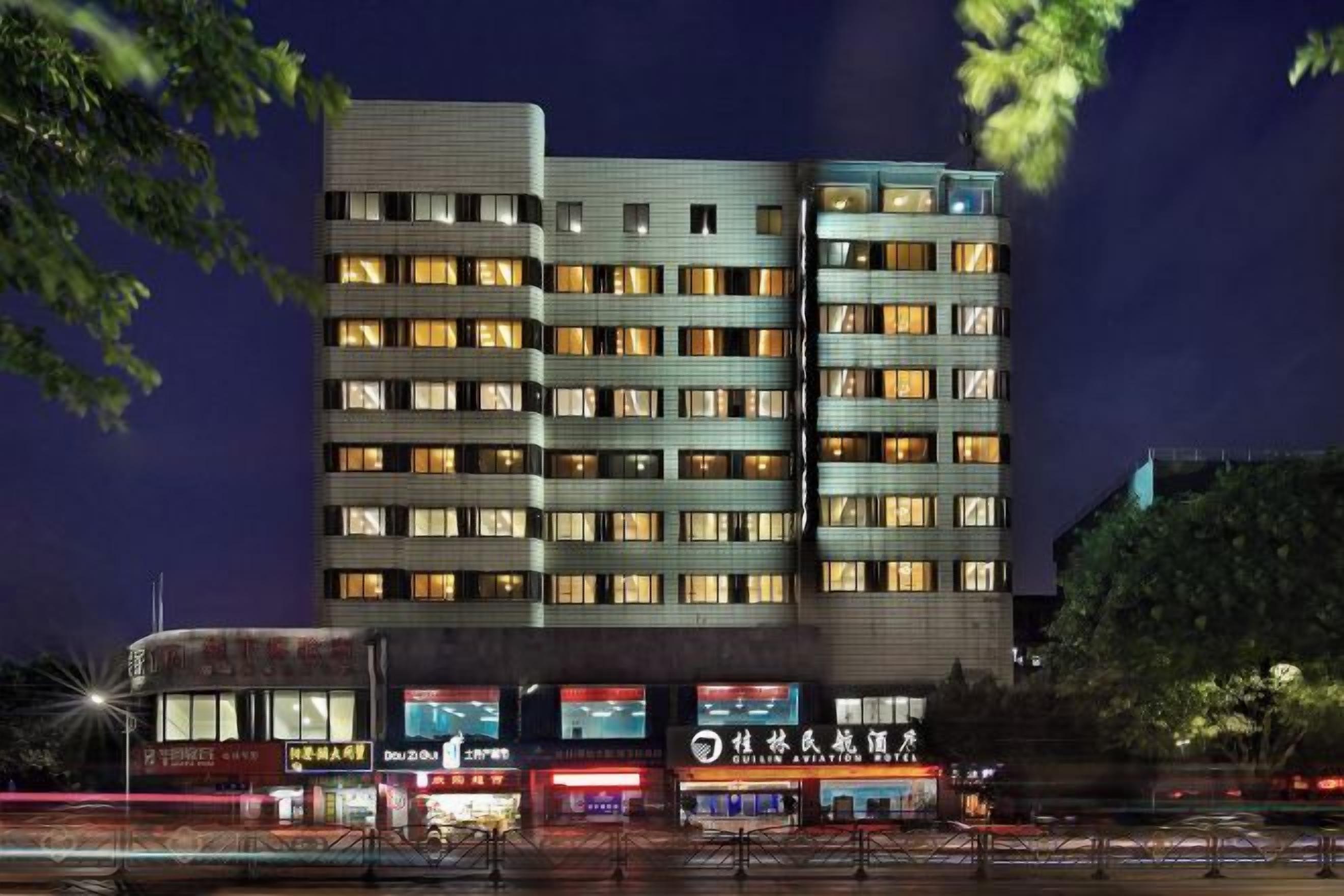 Ein mehrstöckiges Hotel mit moderner Fassade, mehreren Balkonen und beleuchteten Fenstern.